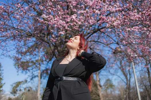 Woman with cherry flowers surrounded by blossoming trees copy space. Beauty and seasonal change and spring bloom season concept