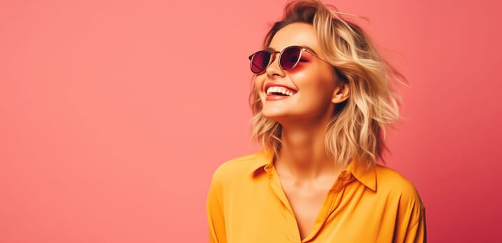 Summer portrait of happy stylish young woman with toothy smile in sunglasses, yellow shirt on pink studio background, looking away