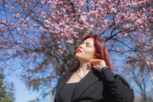 Woman with cherry flowers surrounded by blossoming trees copy space. Beauty and seasonal change and spring bloom season concept