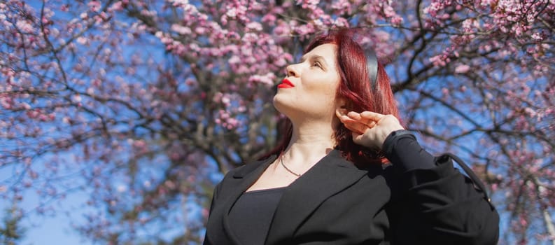 Woman with cherry flowers surrounded by blossoming trees copy space. Beauty and seasonal change and spring bloom season concept