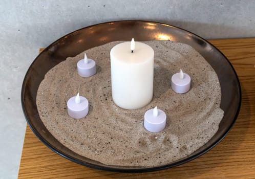 Electric, Led candles in sand in a large bowl. Indoor interior.