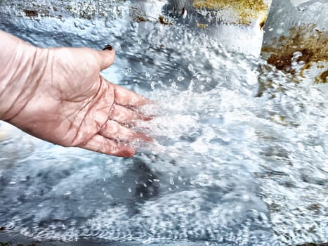 Close-Up of Hand Touching Flowing Water. Hand interacting with water in motion
