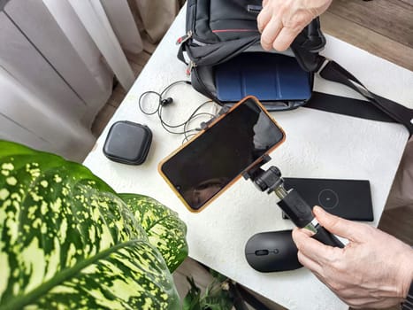 A set of useful blogger devices and hand of female blogger. A neatly organized desk featuring a smartphone, earphones, and various tech gadgets