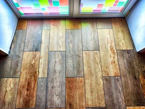 Window and floor. Background, texture. A frosted glass door adorned with vibrant squares allows diffused light into a room with wooden floors
