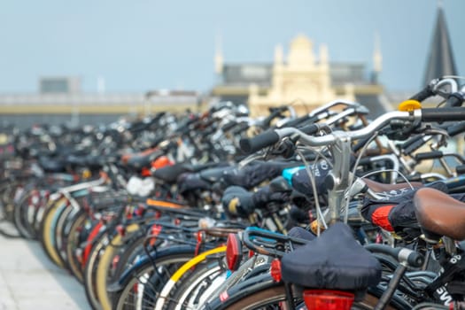 Netherlands. Many bicycles in a bicycle parking lot against the backdrop of an austere facade near Amsterdam Central Station