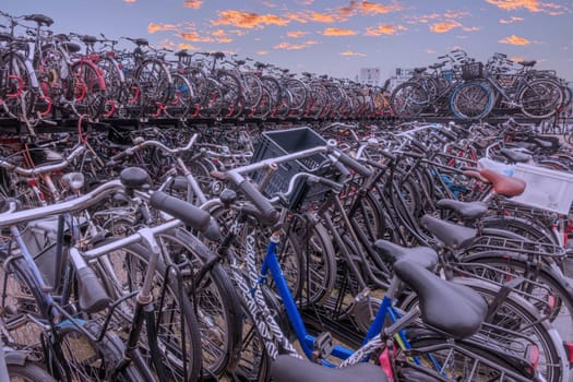 Netherlands. Lots of bicycles in a two-level bicycle parking area near Amsterdam Central Station and a magnificent sunset sky