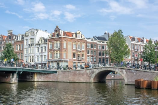 Netherlands. Summer day. Typical Dutch houses on the waterfront of Amsterdam. Stone bridges at the confluence of canals
