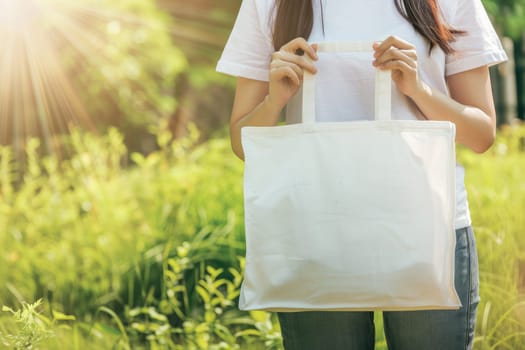 Woman is holding tote bag canvas fabric for mockup blank template, Empty reusable tote bag mockup.