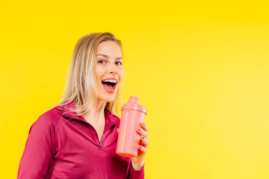 Studio fitness female portrait with bottle of water isolated on a yellow background