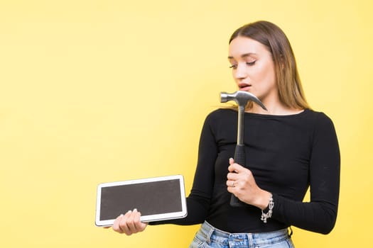 Woman with tablet and a hammer, Studio lighting yellow background isolated, copy space