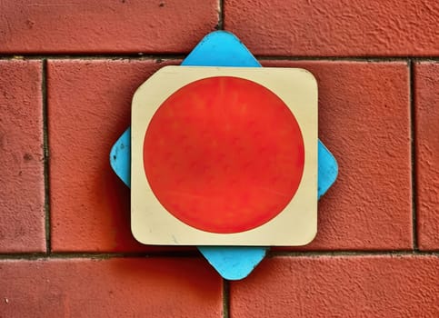 Red and white sign hanging on a textured red brick wall.