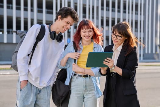 Middle aged business woman agent mentoring teacher social worker working with college university students using digital tablet outdoor