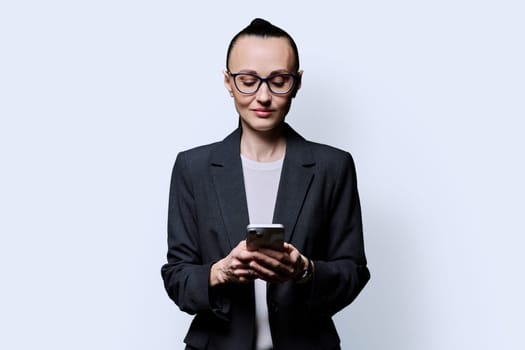 Serious business woman using smartphone on white background. 30s confident successful female holding phone texting reading looking. Mobile internet online technologies apps applications