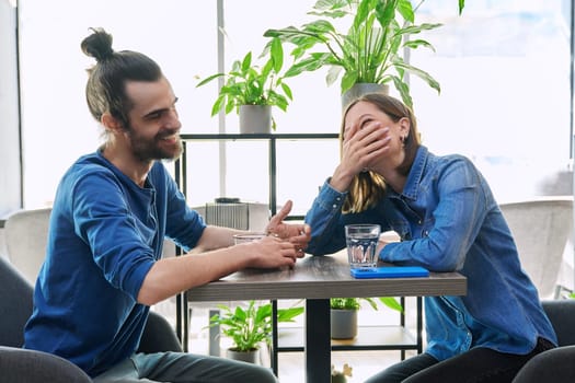 Laughing rejoicing cheerful young couple sitting together at table in cafe. Joyful emotions, enjoyment, friendship, happiness, love, togetherness, lifestyle relationships communication youth concept