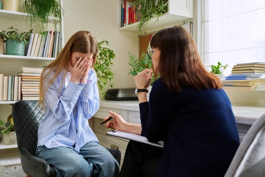 Sad upset young teenage female patient talking to professional mental therapist. Teenager girl high school college student in therapy with psychologist psychotherapist counselor. Psychological health