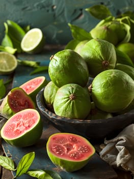 A bowl of fresh green and pink guava fruit, a delicious ingredient for various recipes and dishes, displayed on a wooden table, showcasing natural foods from a terrestrial plant