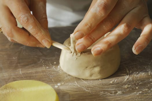 A woman makes a ceramic pot and attaches the legs. Close-up. Creative hobby.