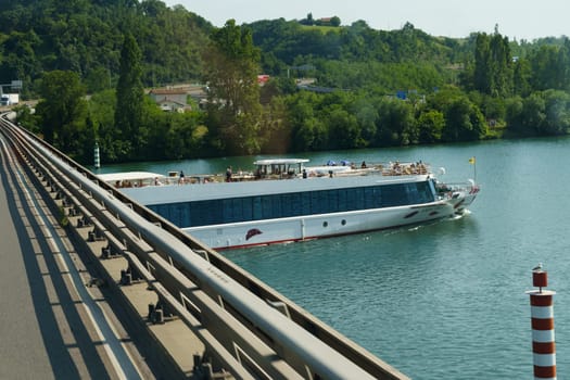 Vaugry Gard, France - May 30, 2023: A significant boat is navigating down a river alongside a bridge, showcasing a typical waterway transport scene.