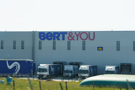 Albon, France - May 30, 2023: A large commercial building BERT and YOU with multiple trucks parked in front of it.
