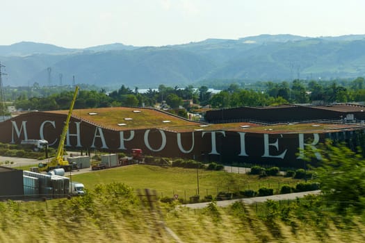 Mercurel-Von, France - May 30, 2023: The M. Chapoutier winery facilities sprawl across a lush hillside, with the golden hue of sunset illuminating the scene.