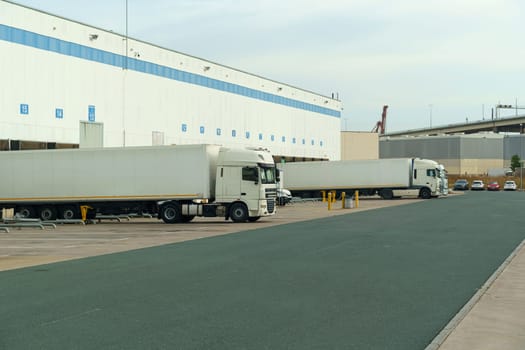 A row of trucks parked neatly in front of a commercial building, showcasing efficient transport and logistics operations.