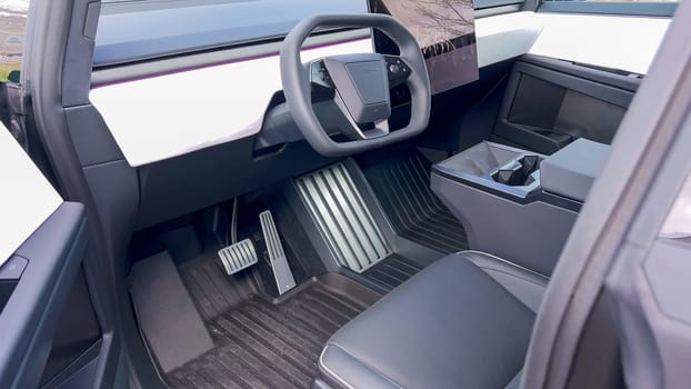 A driver perspective inside the Tesla Cybertruck, highlighting its spacious, minimalist interior with a large touchscreen display and futuristic steering wheel, set against a backdrop of a scenic landscape.