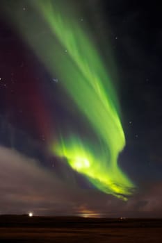Aurora borealis over icelandic scenery, snowy mountains and glowing night sky filled with stars. Northern lights in Iceland forming magical winter landscape, green and yellow colors.