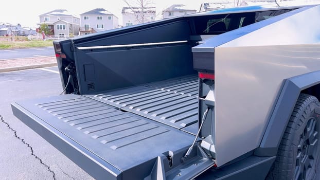 Denver, Colorado, USA-April 28, 2024- Showcasing the utility of the Tesla Cybertruck, this image features the vehicle open cargo bed, highlighting its spacious and functional design, parked in a suburban area with homes in the background.