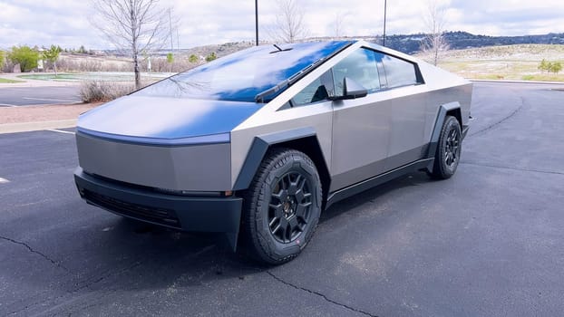 A Tesla Cybertruck stands out with its distinctive, futuristic design and metallic body parked on a suburban street, illustrating the blend of advanced automotive technology with everyday life.