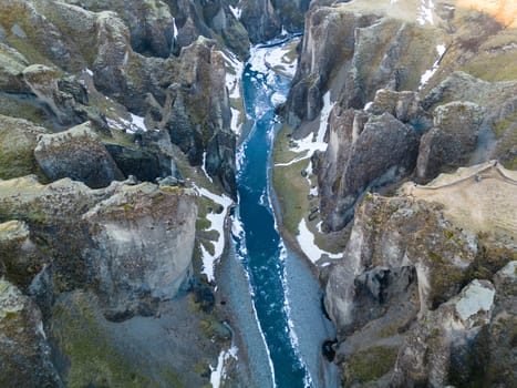 Drone shot of snowy icelandic canyon with frozen water stream and mountains covered in frost creating gorgeous scenery. Magical fjadrargljufur canyon with river in iceland, sightseeing.