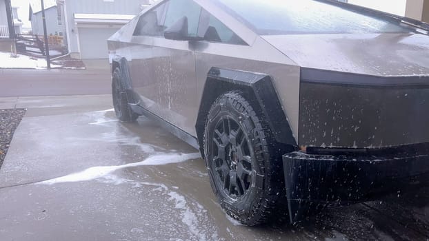 Denver, Colorado, USA-April 28, 2024- The front end of a Tesla Cybertruck is being meticulously cleaned using a high-pressure washer, showcasing the effectiveness of detailed vehicle maintenance and care.