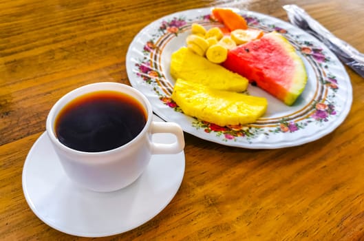 Plate with selected fruits papaya banana watermelon and pineapple and a cup of coffee in Alajuela Costa Rica in Central America.