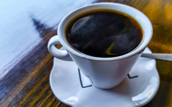 White cup of black Americano coffee on a wooden table in Alajuela Costa Rica in Central America.