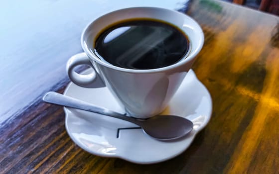 White cup of black Americano coffee on a wooden table in Alajuela Costa Rica in Central America.