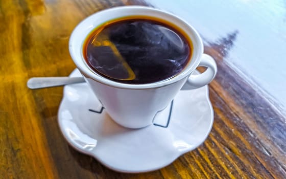 White cup of black Americano coffee on a wooden table in Alajuela Costa Rica in Central America.