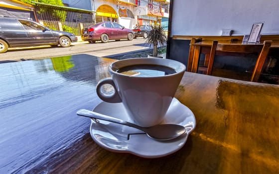 White cup of black Americano coffee on a wooden table in Alajuela Costa Rica in Central America.