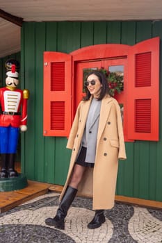 Happy caucasian girl walking Christmas holiday winter day in European city. Brunette woman wears stylish jacket, coat and sunglasses. Positive emotions lifestyle concept. Vertical photo, full length