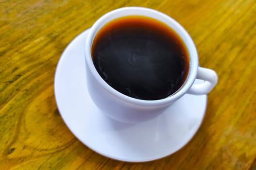 White cup of black Americano coffee on a wooden table in Alajuela Costa Rica in Central America.