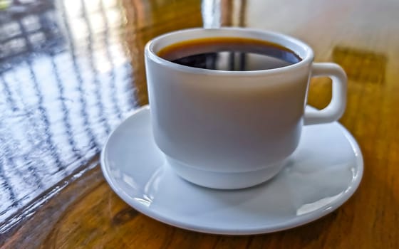 White cup of black Americano coffee on a wooden table in Alajuela Costa Rica in Central America.