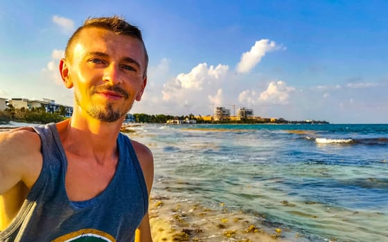 Male tourist Travelling man taking selfie photo on the beach in Playa del Carmen Quintana Roo Mexico.