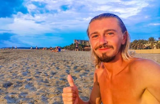 Male tourist traveler man makes selfie with beautiful rocks cliffs stones boulders and huge big surfer waves and natural panorama view on the beach in Puerto Escondido Oaxaca Mexico.