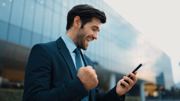 Successful business man celebrate increasing sales while standing. Happy project manager or leader proud with successful project, getting a promotion, getting a job while holding a phone. Exultant.