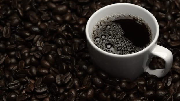 Top view of coffee or espresso with piles of coffee beans. Close up of fresh roasted coffee bean scatter around wooden table with cup of americano and aromatic stream and smoke from seed. Comestible.