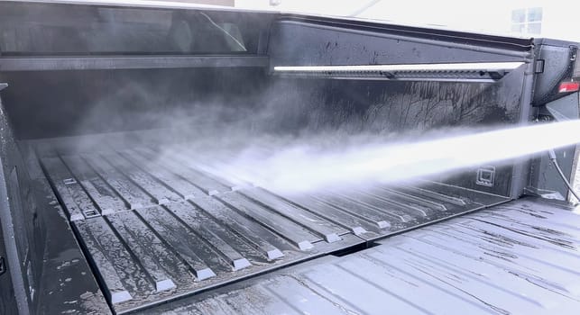 Denver, Colorado, USA-April 28, 2024- This image captures a Tesla Cybertruck undergoing a thorough cleaning, focusing on the high-pressure washing of its cargo bed, demonstrating the maintenance of its durable and robust design. High-Pressure Cleaning of the Tesla Cybertruck Cargo Bed. High quality photo