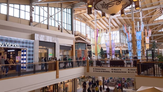 Denver, Colorado, USA-April 28, 2024- Capturing the expansive and airy interior of Park Meadows Mall, this image highlights the modern architectural style with wooden beams, large hanging lights, and a series of vibrant hanging ribbons, creating a lively shopping atmosphere.