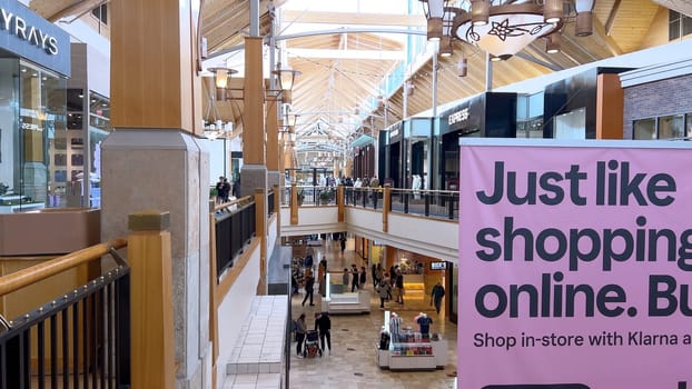 Denver, Colorado, USA-April 28, 2024- Capturing the expansive and airy interior of Park Meadows Mall, this image highlights the modern architectural style with wooden beams, large hanging lights, and a series of vibrant hanging ribbons, creating a lively shopping atmosphere.