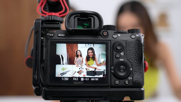 Rear view behide camera screen display two women influencer shoot live streaming vlog video review makeup social media or blog. Girl with cosmetic vivancy studio lighting for marketing recording.