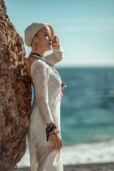 Middle aged woman looks good with blond hair, boho style in white long dress on the beach decorations on her neck and arms