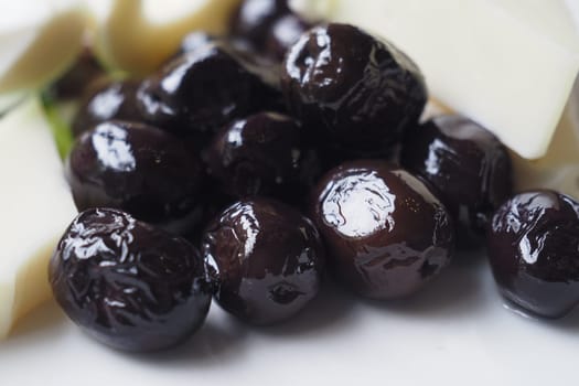 Collection of black olives with cheese on a plate .,