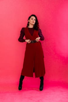 A woman in a red dress poses for the camera. She is wearing black boots and a belt